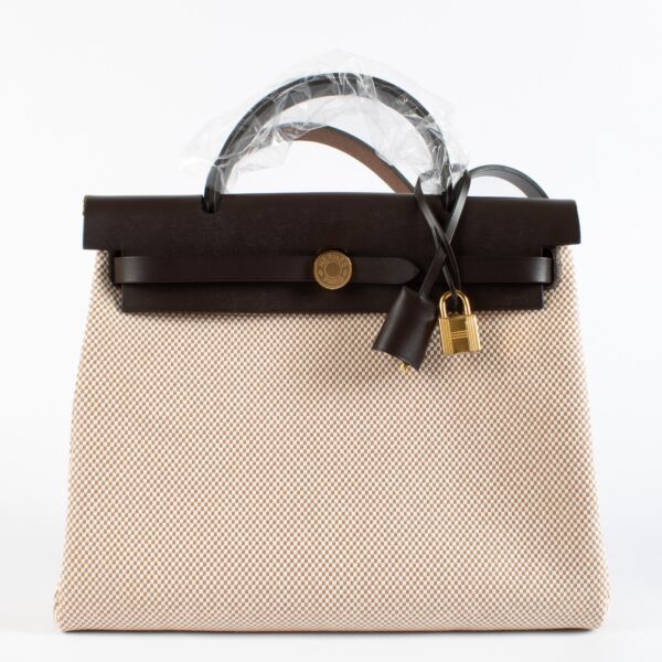 Effortlessly blending sporty sophistication with timeless Hermès craftsmanship, the Herbag Zip 31 Retourne is the epitome of understated luxury. This Hermès Herbag 31 features a structured top-handle silhouette crafted in durable Écru canvas with tonal Bé
